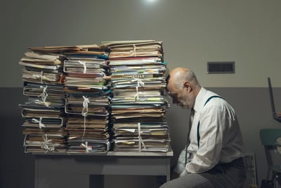 tired-man-leaning-his-head-against-a-ptired  fleet manager leaning his head against a pile of paperwork