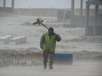 Construction Worker Walking in the Rain to manually take fuel tank readings.