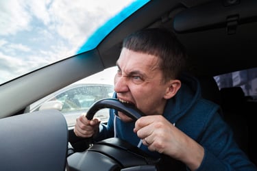Frustrated fleet vehicle driver biting the steering wheel because of steering, transmission or suspension failures.