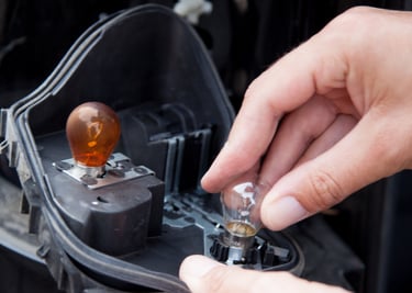 Man changing blown bulb in headlights of a fleet truck.