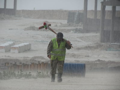Construction Worker Walking in the Rain to manually take fuel tank readings.