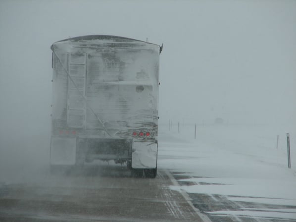 fleet truck on snowy road in poor driving conditions
