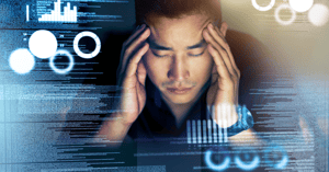 man in front of computer screen holding his head due to fleet management information overload,