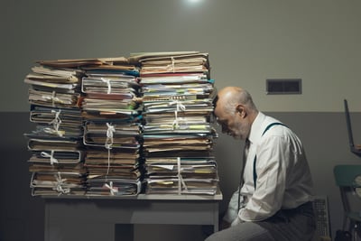 tired-man-leaning-his-head-against-a-pile-of-paperwork